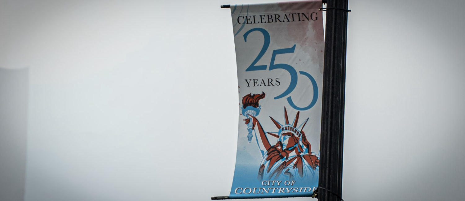 A street banner attached to a lamp post reads "Celebrating 250 Years" and "City of Countryside," with a illustration of the Statue of Liberty against a light blue background.