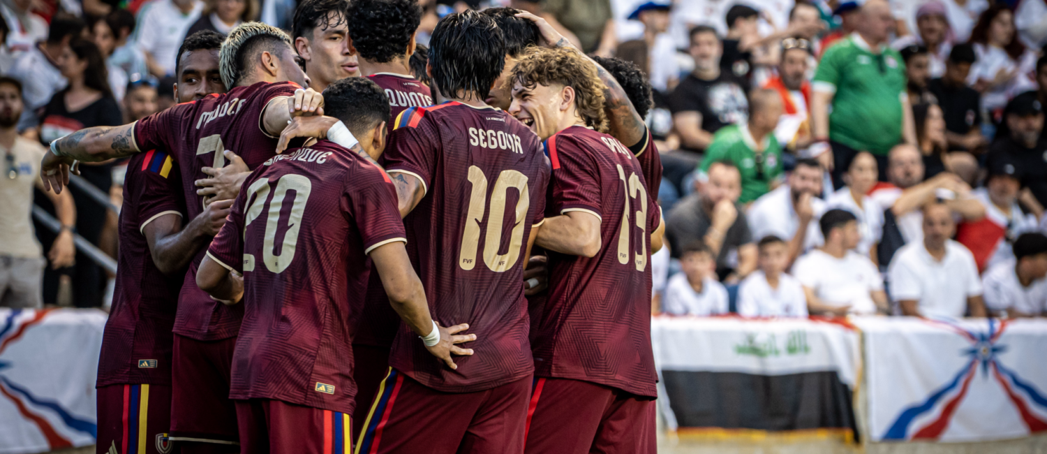 Soccer team celebrates together after scoring a goal in front of the crowd.