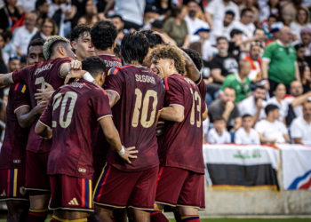 Soccer team celebrates together after scoring a goal in front of the crowd.