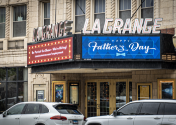 Front entrance of the LaGrange Theater with a marquee displaying "Happy Father's Day" and a hiring announcement, with cars parked along the street.