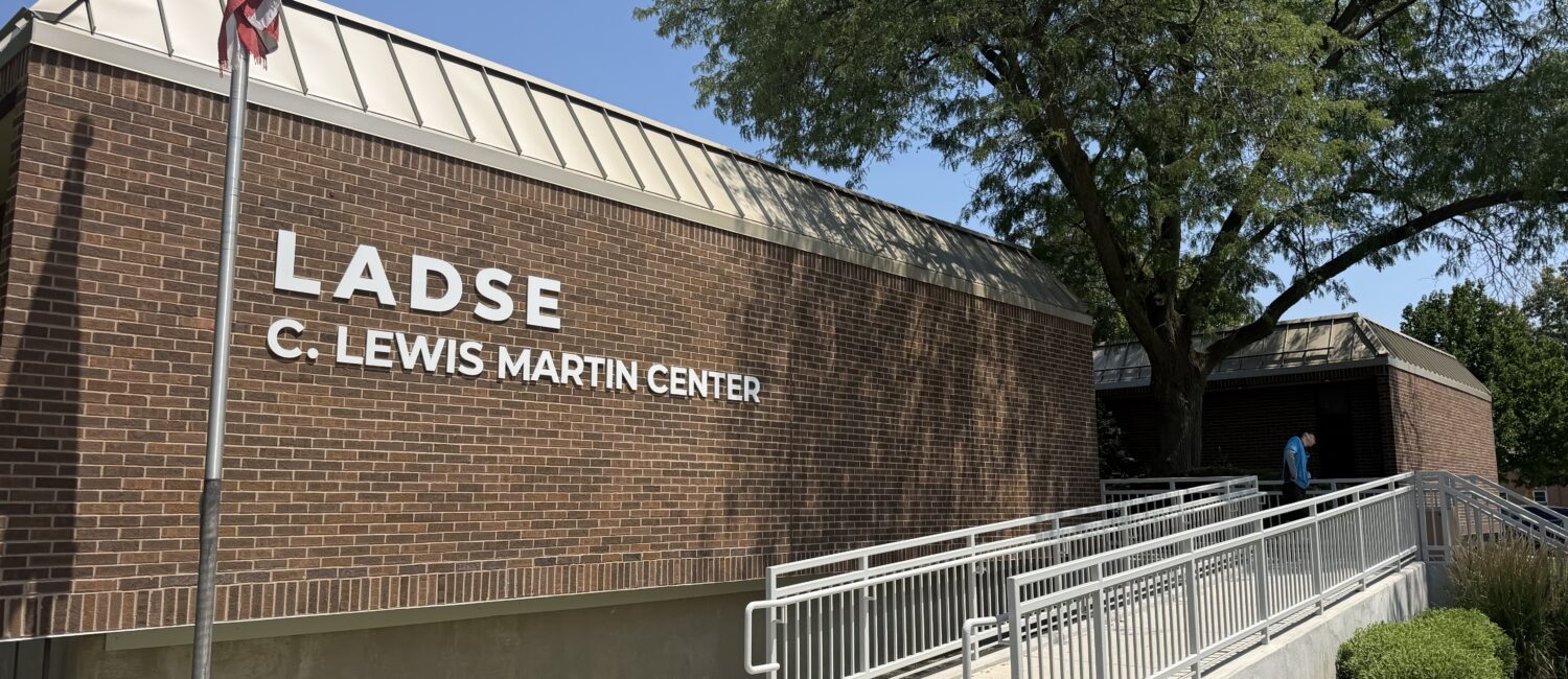 Brick LADSE C. Lewis Martin Center building with an American flag, accessible ramp, and large tree outside.
