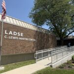 Brick LADSE C. Lewis Martin Center building with an American flag, accessible ramp, and large tree outside.