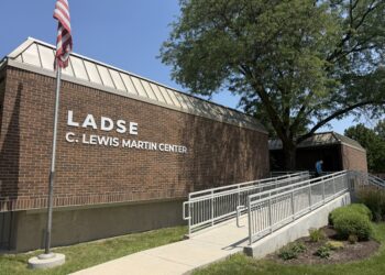 Brick LADSE C. Lewis Martin Center building with an American flag, accessible ramp, and large tree outside.