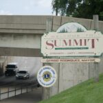 Welcome sign for the Village of Summit beside a road leading under an overpass.
