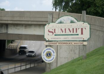 Welcome sign for the Village of Summit beside a road leading under an overpass.